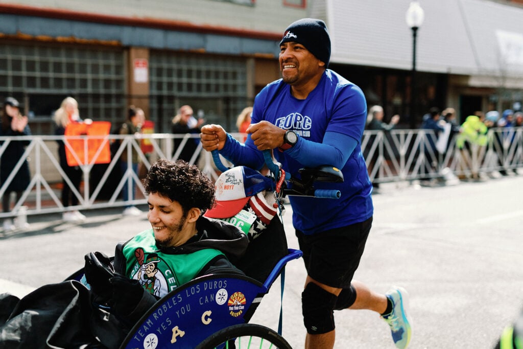 A father races with his son in a wheelchair at the New Bedford Half Marathon. Photo by Maggie Howland. A father runs pushing his son in a wheelchair in the New Bedford Half Marathon.