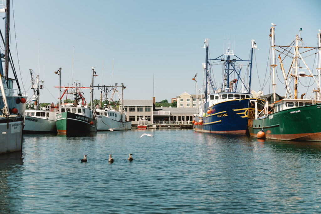 Summer in the Seaport of New Bedford Massachusetts view from the water with fishing boats and a waterfront restaurant.